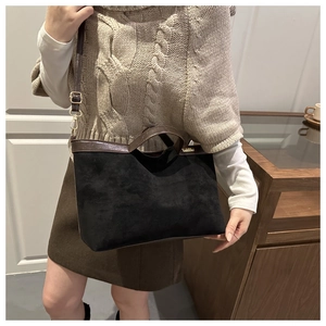 Detail of suede and brown leather tote bag with gold logo plate and adjustable strap