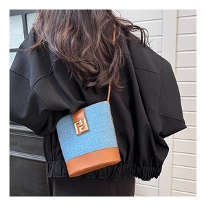 Detail of denim and brown leather crossbody bucket bag with gold logo buckle on model
