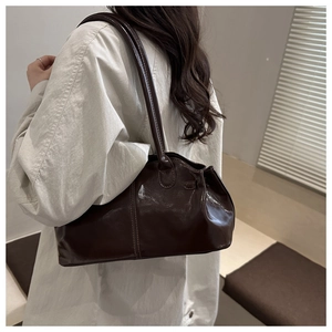 Dettaglio della borsa a tracolla in pelle marrone caffè lucida con texture liscia e doppi manici