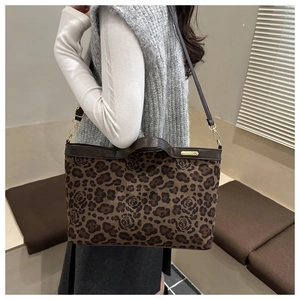 Detail of leopard and rose print tote bag with brown leather strap and gold hardware