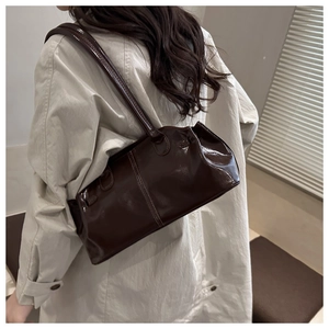 Dettaglio di una borsa a spalla in vernice marrone scuro lucida in stile retrò baguette