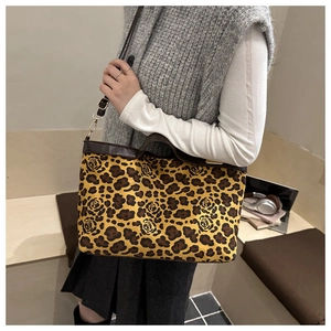 Detailed view of leopard and rose print tote bag with brown leather handles and strap
