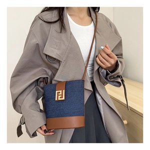 Detail of vintage denim and brown leather bucket bag with gold geometric metal buckle