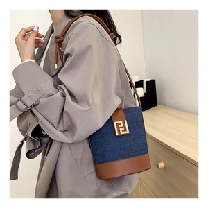 Detail of denim and leather bucket bag with knotted strap and gold metal buckle