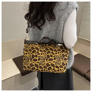 Detail of adjustable leather strap and golden logo on leopard rose print tote bag