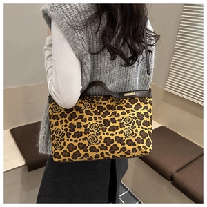 Detail of leopard and rose print tote with brown leather trim and gold metal logo plaque