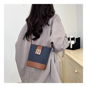 Modern denim bucket bag with leather trim worn as a crossbody bag on model back view