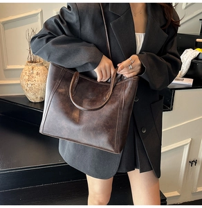 Detail of dark brown vintage oil wax leather tote bag with handles and adjustable strap