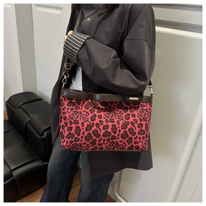 Detail of red leopard print tote with rose patterns and brown leather strap and buckle