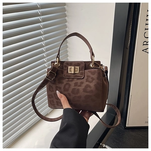 Macro view of leopard print faux suede handbag with a square gold twist-lock buckle