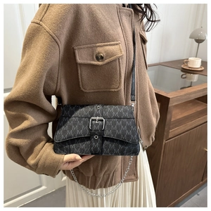 Détail du sac à bandoulière vintage noir avec motif M gris et boucle en métal argenté