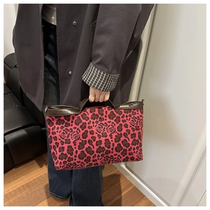 Close-up of leopard and rose print handbag with brown leather handles and gold metal tag