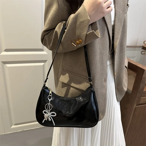 Glossy black hobo shoulder bag with a silver beaded bow charm shown on model