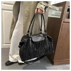 Detail of black pleated shoulder bag with embossed fashion logo and gold hardware