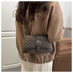 Close-up of vintage brown crossbody bag with M-pattern print and silver chain strap