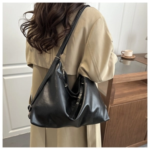 Détail du sac cabas en cuir noir minimaliste avec œillets métalliques sur le côté