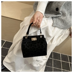Detail of black faux leopard texture handbag with elegant gold twist lock and handle