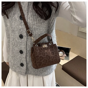 Close-up of leopard print crossbody bag with gold metal clasp on a casual autumn outfit