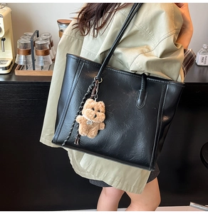 Detailed close-up of large black tote bag with cute brown plush puppy charm