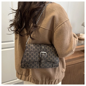 Detail of printed crossbody bag with silver chain and M pattern on brown leather