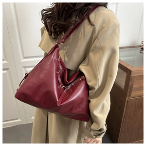 Détail du sac cabas en cuir bordeaux montrant les ferrures métalliques et le profil latéral