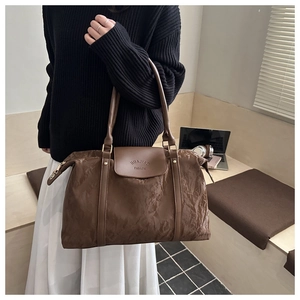 Detail of glossy brown wrinkled leather texture and handle on large tote bag