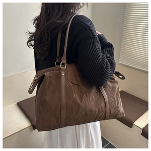 Detail of large brown leather tote bag showing textured finish and fashion stamp