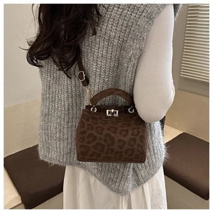 Détail du sac seau léopard avec boucle en métal sur texture en daim élégante