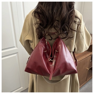 Vue de dos du grand sac fourre-tout vintage bordeaux porté avec un trench-coat décontracté