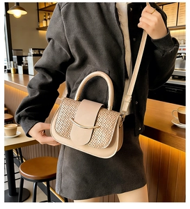 Close-up of elegant apricot woven texture handbag with golden metal hardware and strap