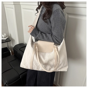Close-up of beige textured tote bag with HUAJIAO FASHION logo and leather handles