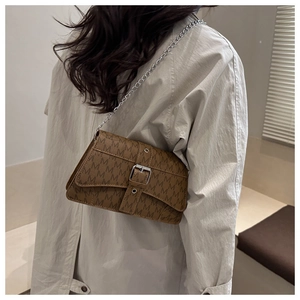 Detail of brown crossbody bag featuring retro M pattern and silver chain strap on model