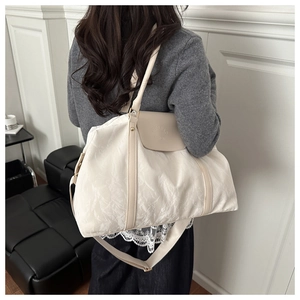 Detail of a large cream tote bag with unique pleated texture and embossed fashion logo