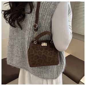 Détail du sac à main léopard avec fermoir doré porté sur un pull en maille grise