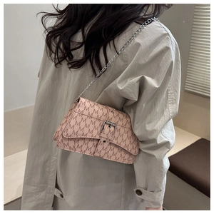 Detail view of pink crossbody bag with M-pattern print and silver chain strap on model