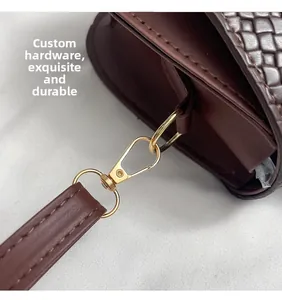 Macro view of golden hardware and woven texture on a dark brown leather saddle bag