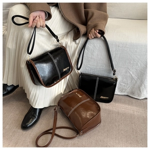 Detail of minimalist leather crossbody bags showing glossy finish and contrast stitching