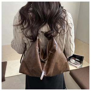 Détail d'un grand sac cabas en similicuir marron avec fermetures éclair et boucle