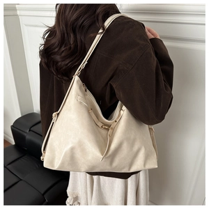 Vue latérale du grand sac hobo crème montrant les sangles réglables et le cuir texturé souple