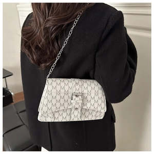 Mannequin portant un sac bandoulière rétro à motif M avec chaîne et boucle argentée