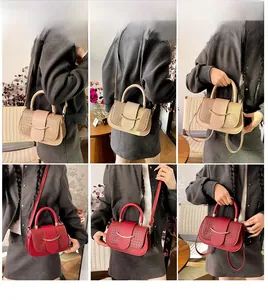 Détail du sac selle pour femme en beige et rouge avec texture tressée et boucle métal