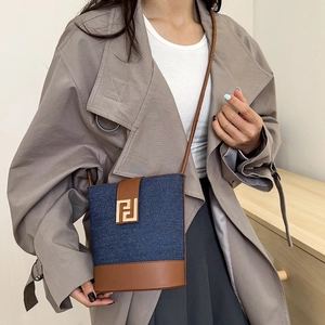 Denim and brown leather bucket bag with gold geometric buckle and shoulder strap