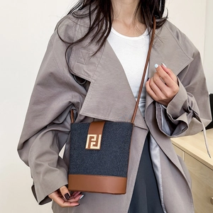 Retro denim bucket bag with brown leather trim and golden hardware shown on a model