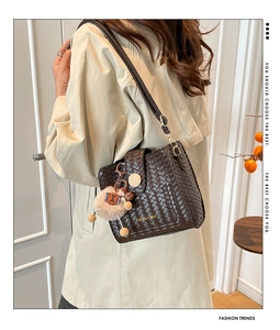 Detail of hand-woven dark brown leather crossbody bag with wooden buckle and plush bear