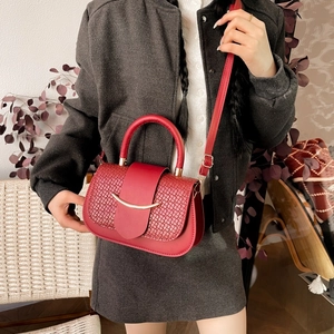 Détail du sac selle rouge avec textures tissées et fermoir métallique doré courbé