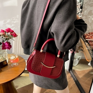 Close-up of red leather underarm bag with woven texture and crescent gold buckle