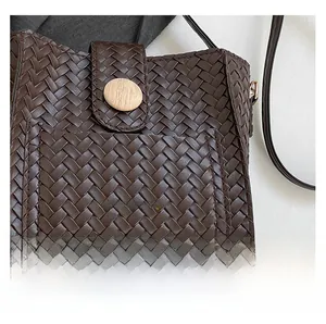 Detail of woven texture on dark brown crossbody bag with round wooden magnetic buckle