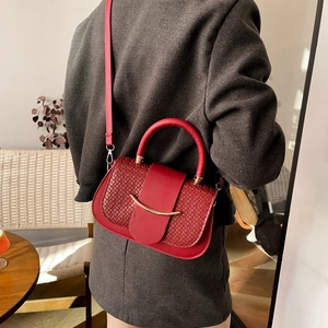 Sac bandoulière rouge avec texture tressée et détails métalliques dorés vus de dos
