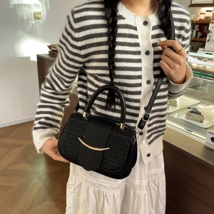 Détail du sac à main noir avec texture tressée et boucle métallique dorée courbée