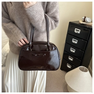 Vue détaillée d'un sac polochon en cuir marron foncé avec un nœud et un logo imprimé